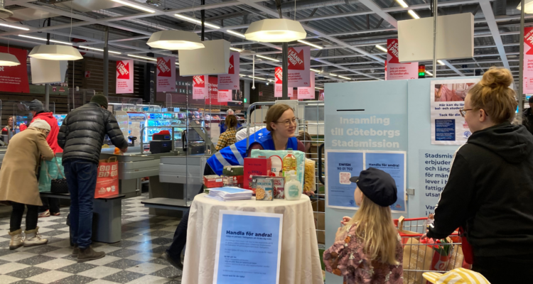 Person från Göteborgs Stadsmission tar emot matvaror från barn.