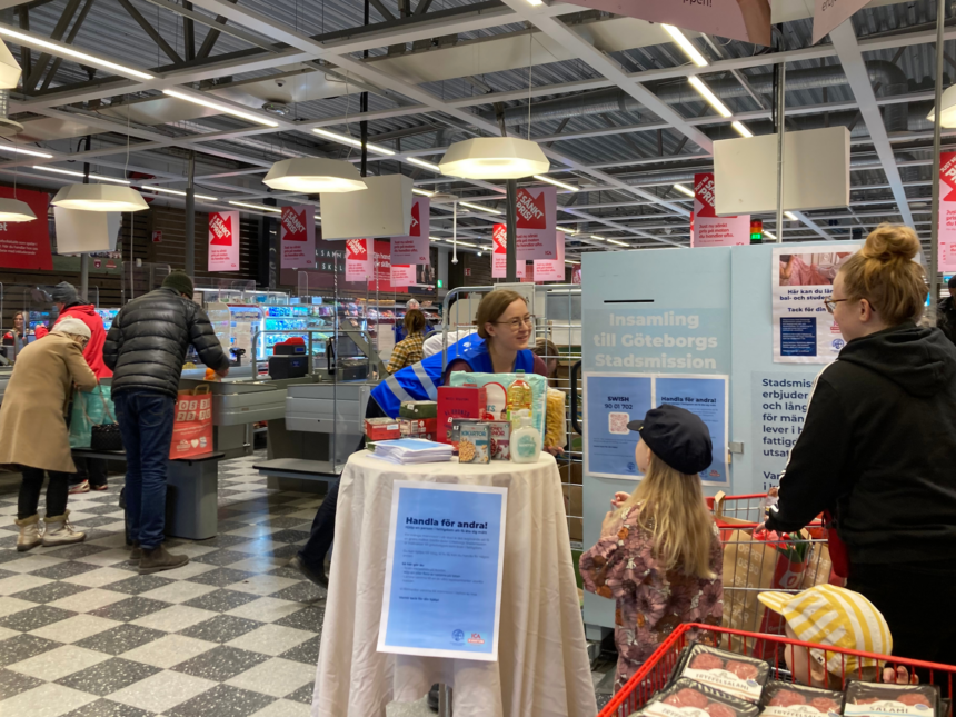 Person från Göteborgs Stadsmission tar emot matvaror från barn.